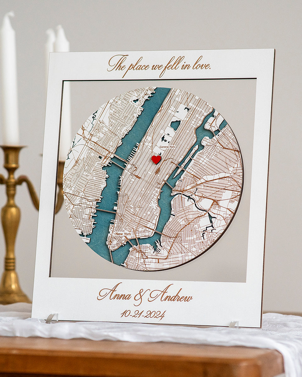 Framed map with a red heart and personalized text on a table with candles in the background