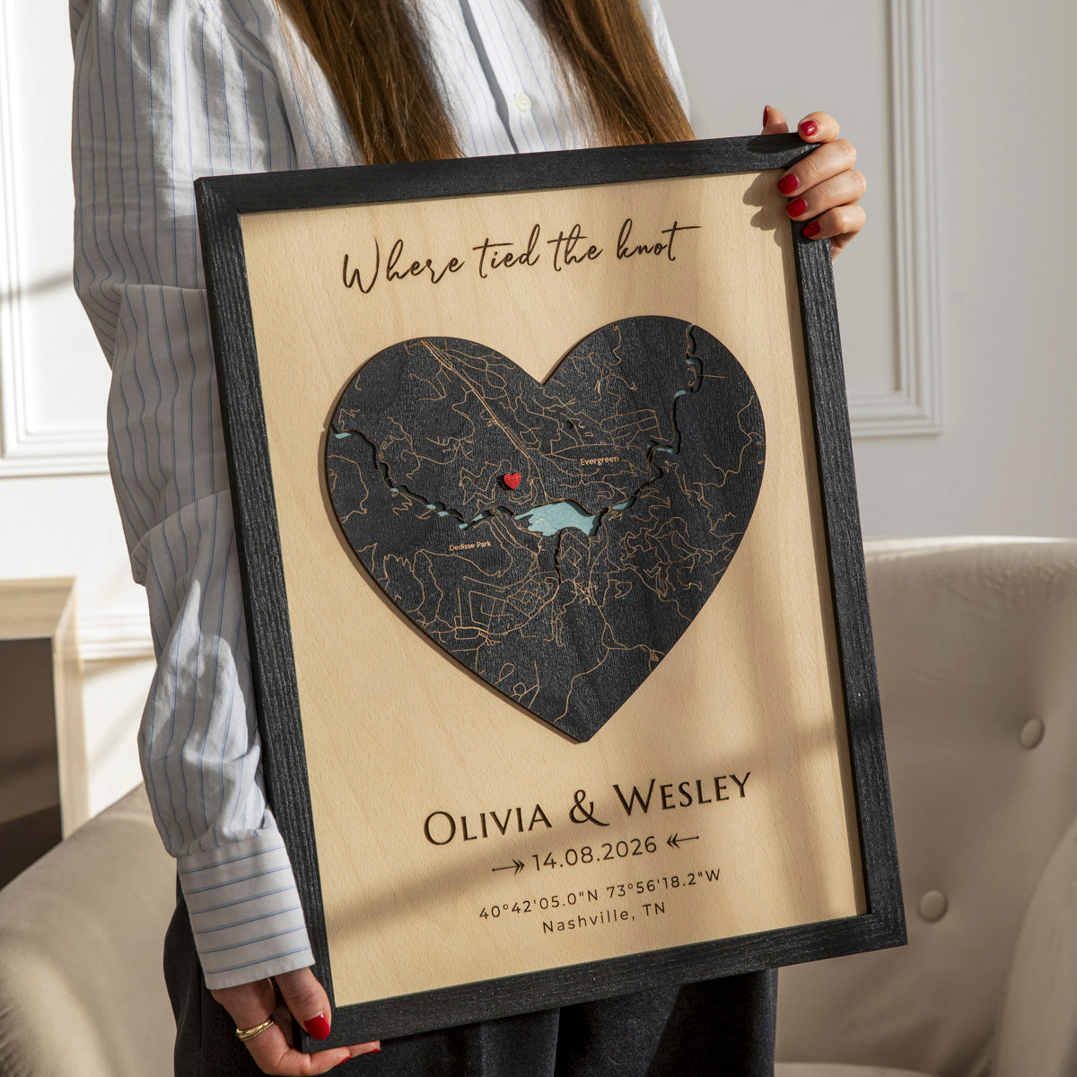 Woman holding personalized 3D wooden wedding wall art with heart map, names, date, and custom coordinates.