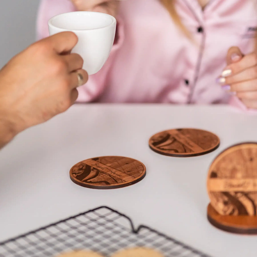 Engraved wooden coaster set with holder used on table with coffee cups as a personalized gift set