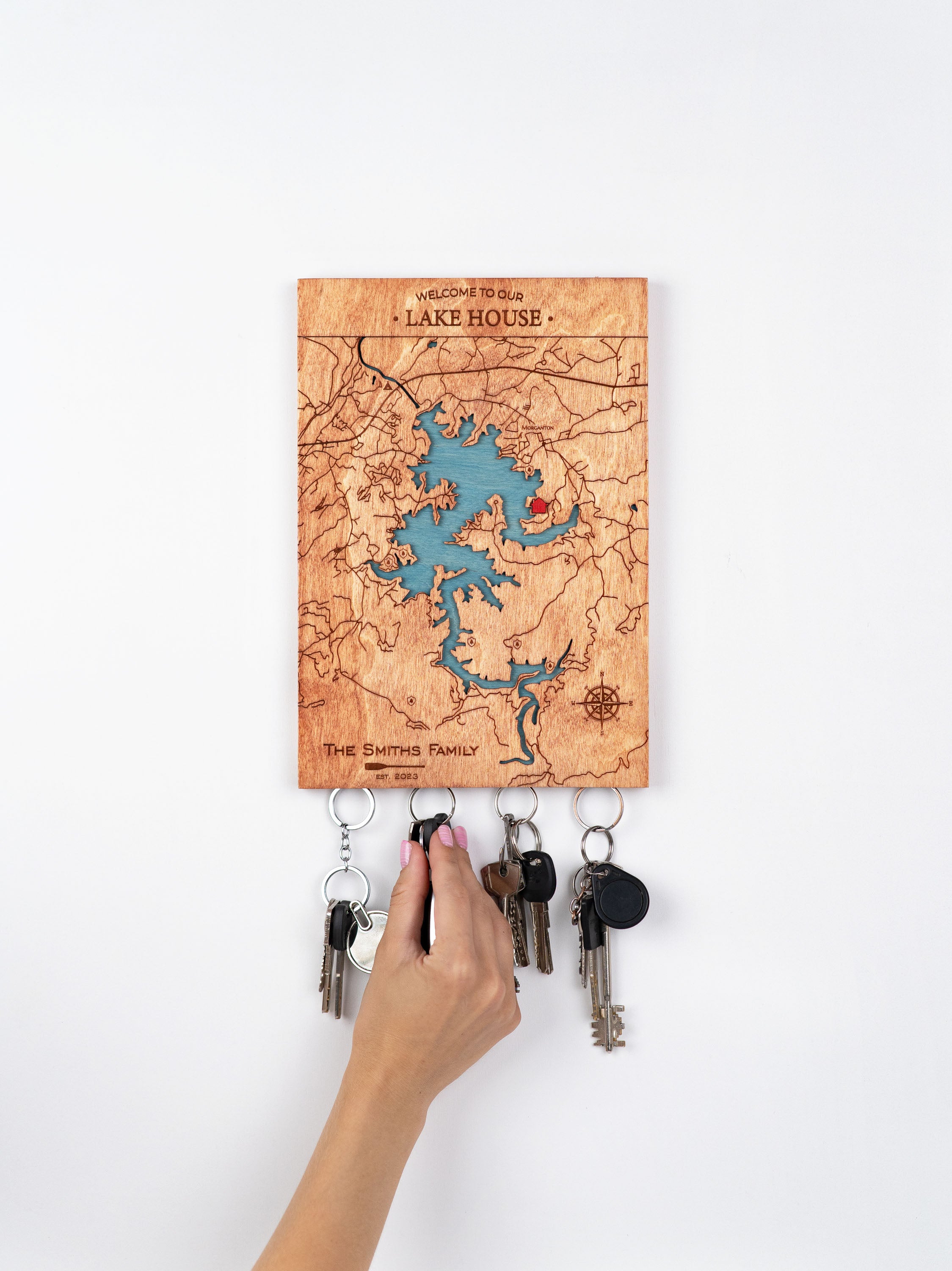 Wooden key holder with detailed map design with lake patterns. It says WELCOME TO OUR LAKE HOUSE. Several keys hang on strong magnetics.