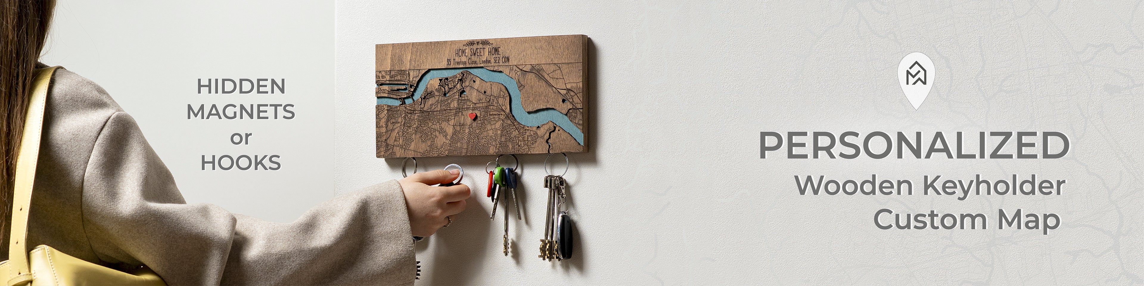 Person using a personalized wooden keyholder with a custom map design on a light gray background.