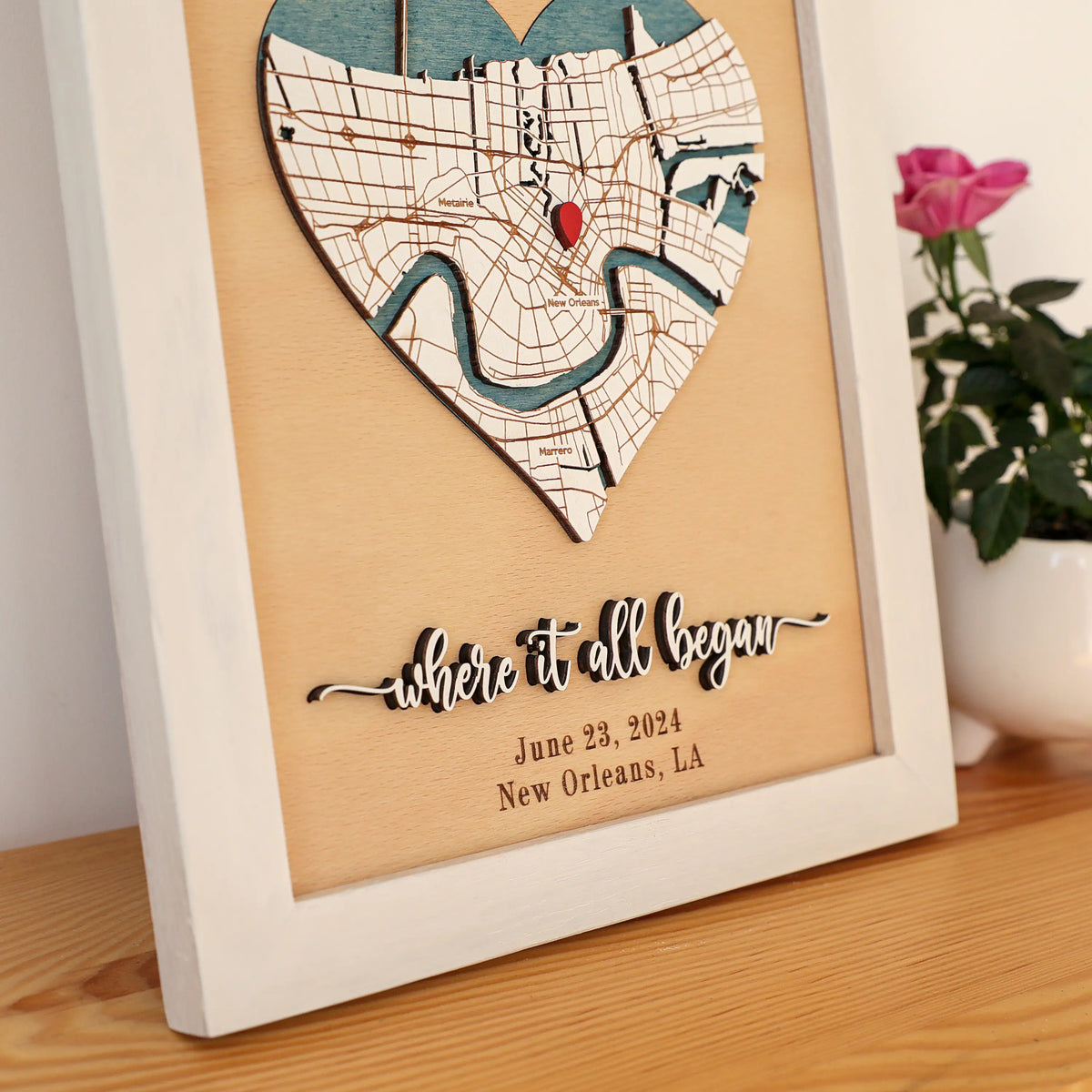 Close-up of 3D wood heart map with layered streets, blue water details, red location pin, and Where It All Began anniversary cutting.