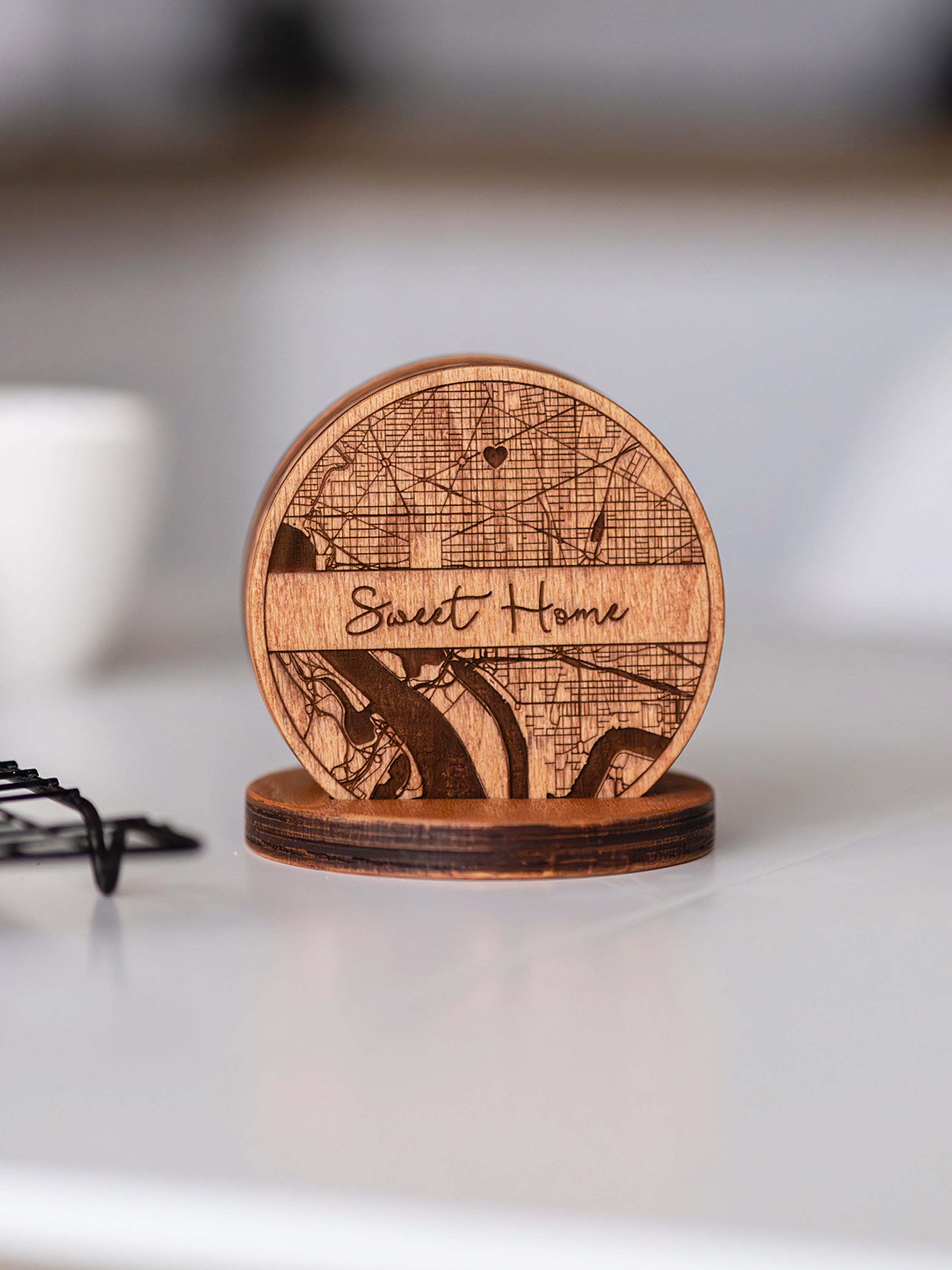 Wooden coaster with a string art design that says "Sweet Home" on a background of a map location.
