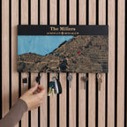 Hand using wooden magnetic key holder for wall with custom coordinates in black finish