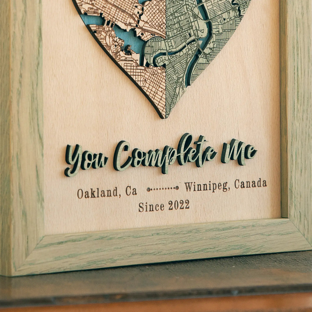 Close-up of custom heart map with raised 3D wooden lettering, personalized locations, date, and sage oak frame.