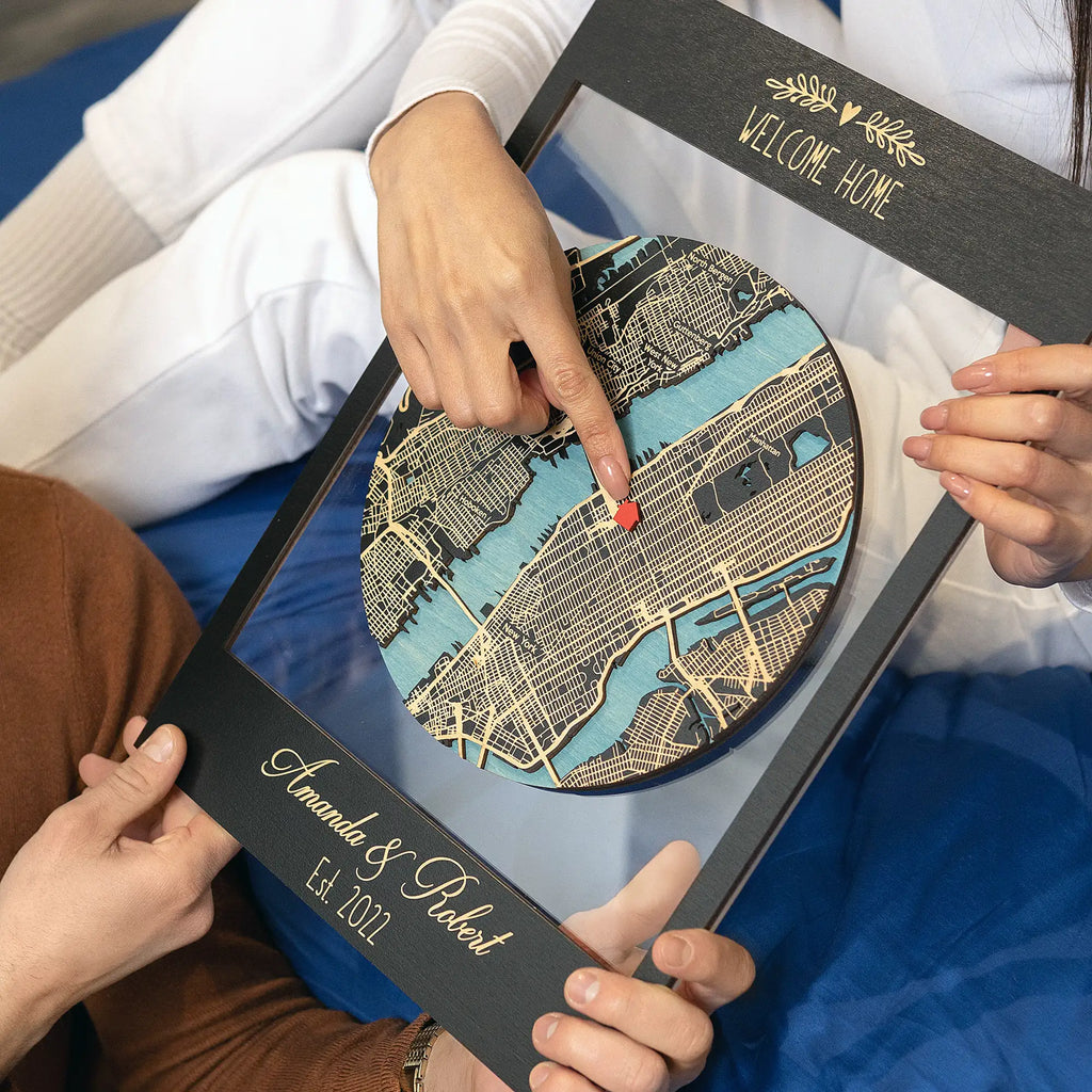Couple holding personalized framed wooden map and pointing to home location, custom housewarming gift for new homeowners