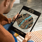 Man holding personalized 3D wooden location art in black frame, custom welcome home gift with names and established date