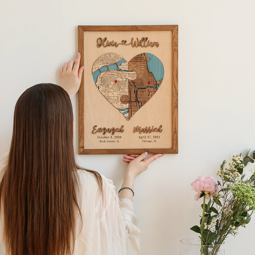 Custom wedding gift map being placed on the wall, featuring two locations, raised wooden names, and milestone dates.