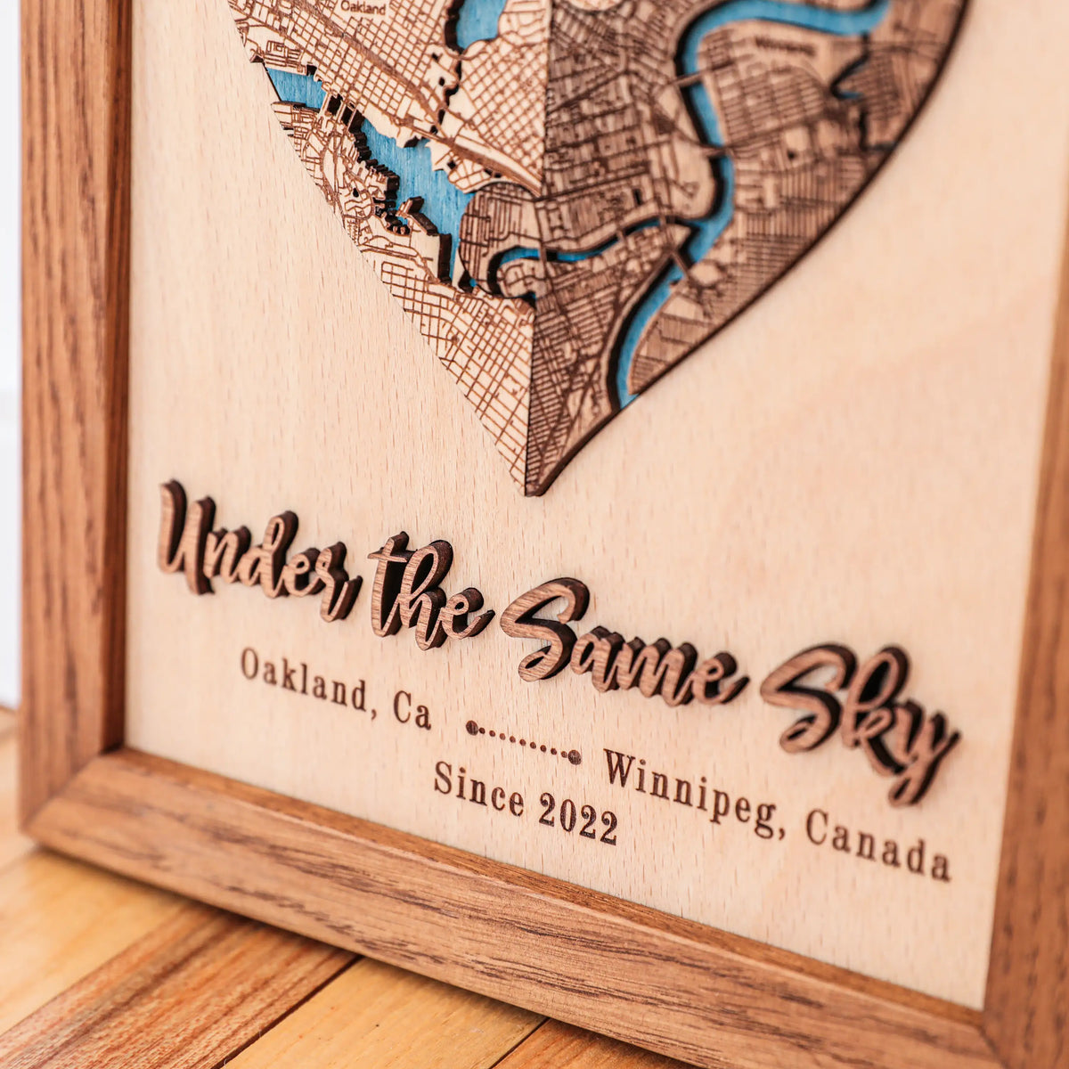 Close-up of custom wooden map with raised 3D phrase, personalized city names, date, and Early American frame.