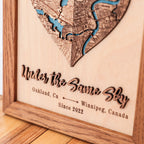 Close-up of custom wooden map with raised 3D phrase, personalized city names, date, and Early American frame.