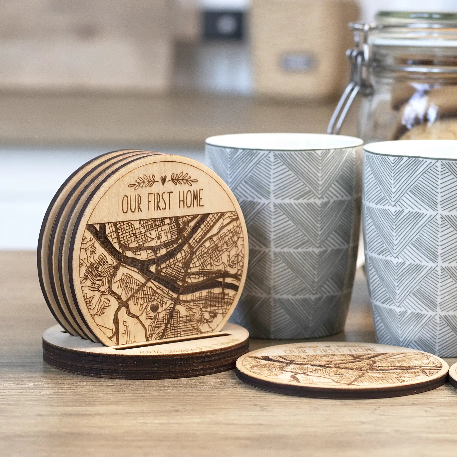 Engraved wooden coasters with custom city map design beside mugs, personalized coaster set with holder included