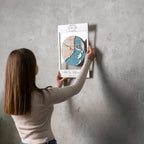 Woman hanging personalized First Home map on wall in white frame with custom location design