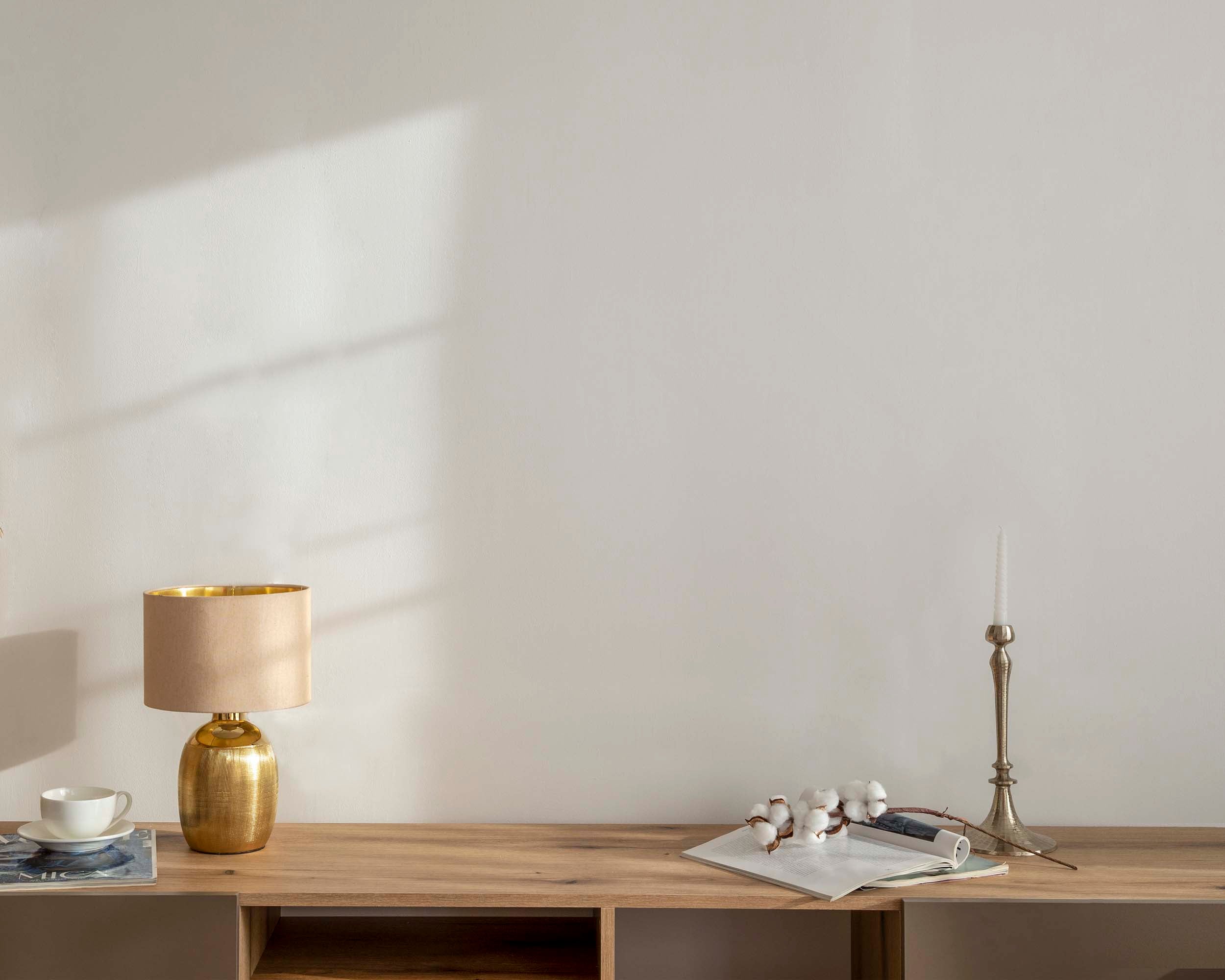 Gold lamp on a wooden desk with a white wall background Empty wall vs decorated wall 