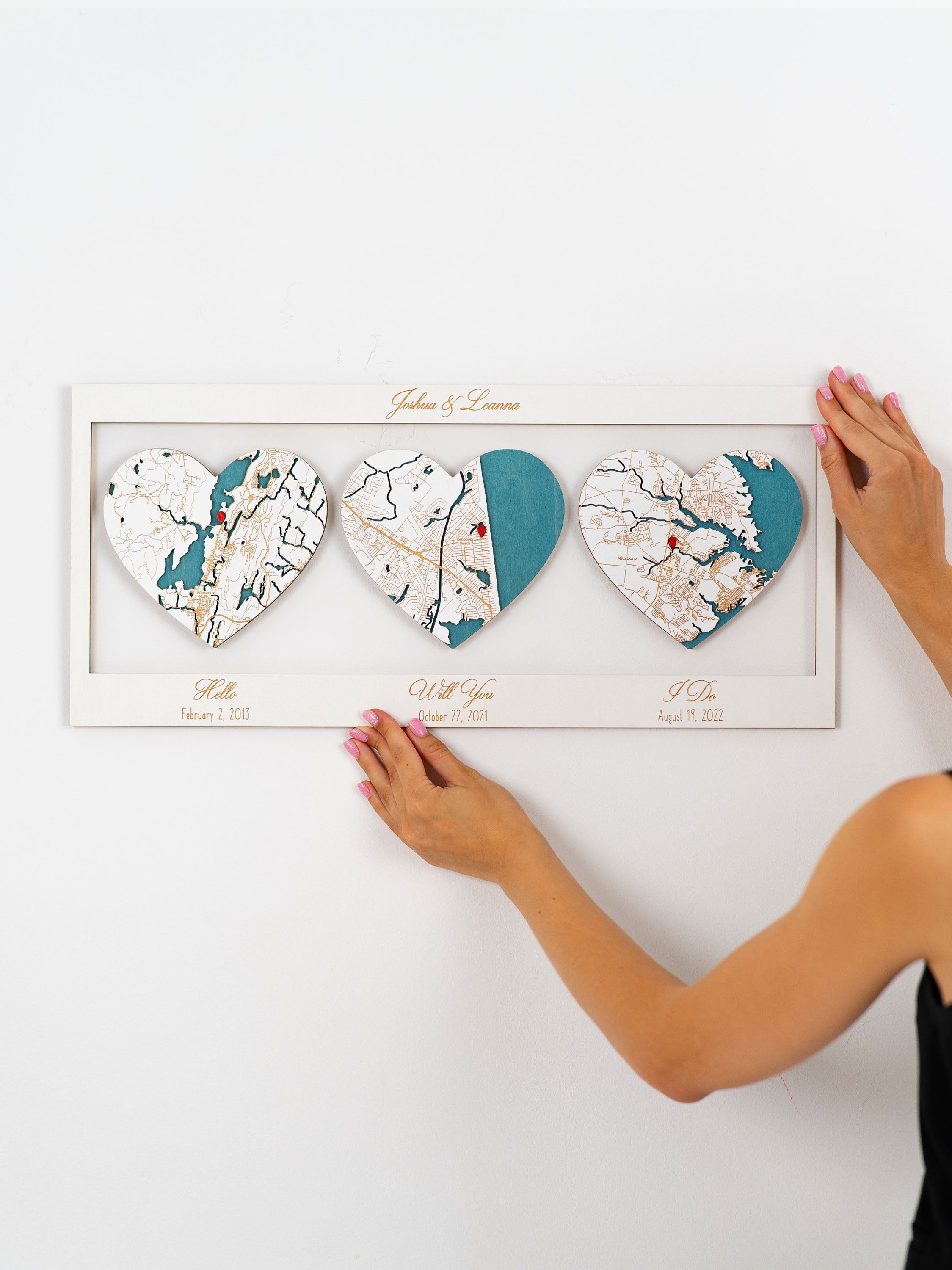 Customized map artwork with three heart-shaped cutouts featuring maps and significant dates, titled "Hello Will You I Do," personalized with names atop, indicating keys and locations in a couple's relationship on. The frame has personalized text.