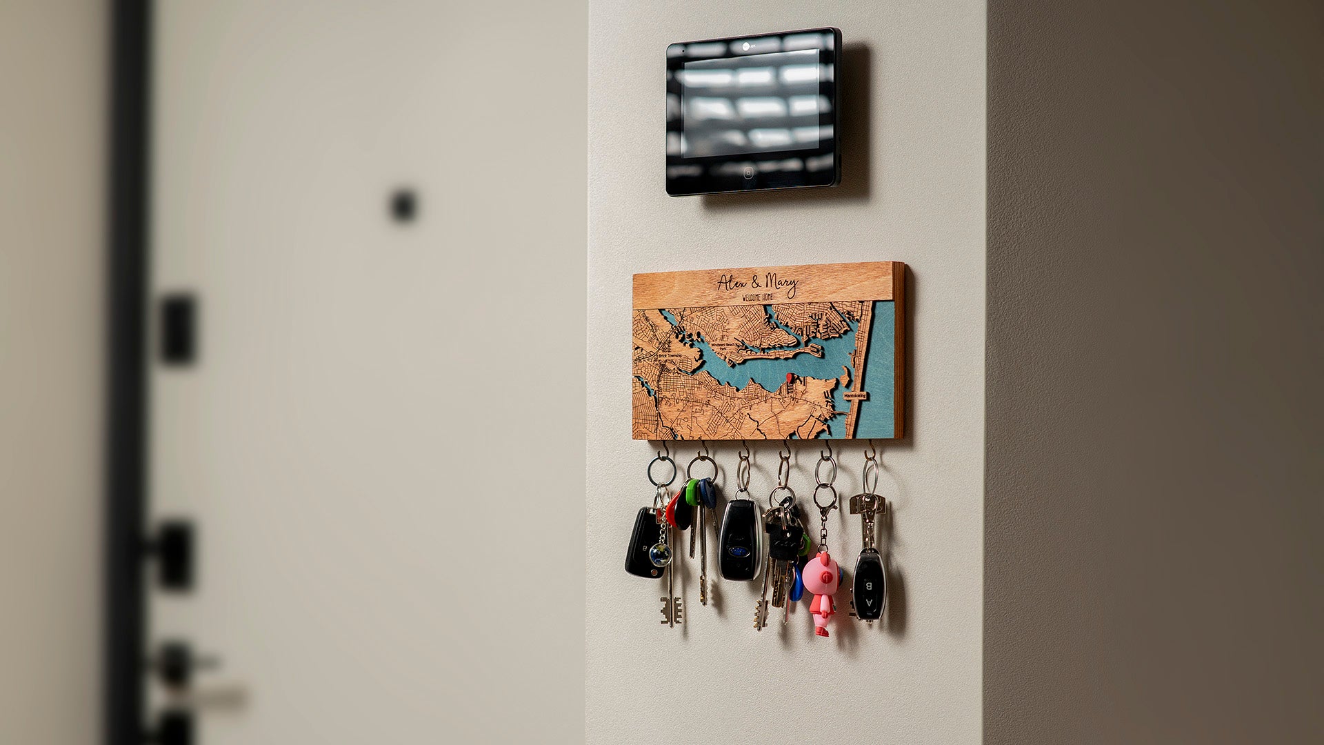 Wooden key holder for wall with custom map featuring laser-cut streets and blue water details, mounted in an entryway with keys hanging from hooks