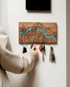 Person using a key holder with a map design on a white wall.