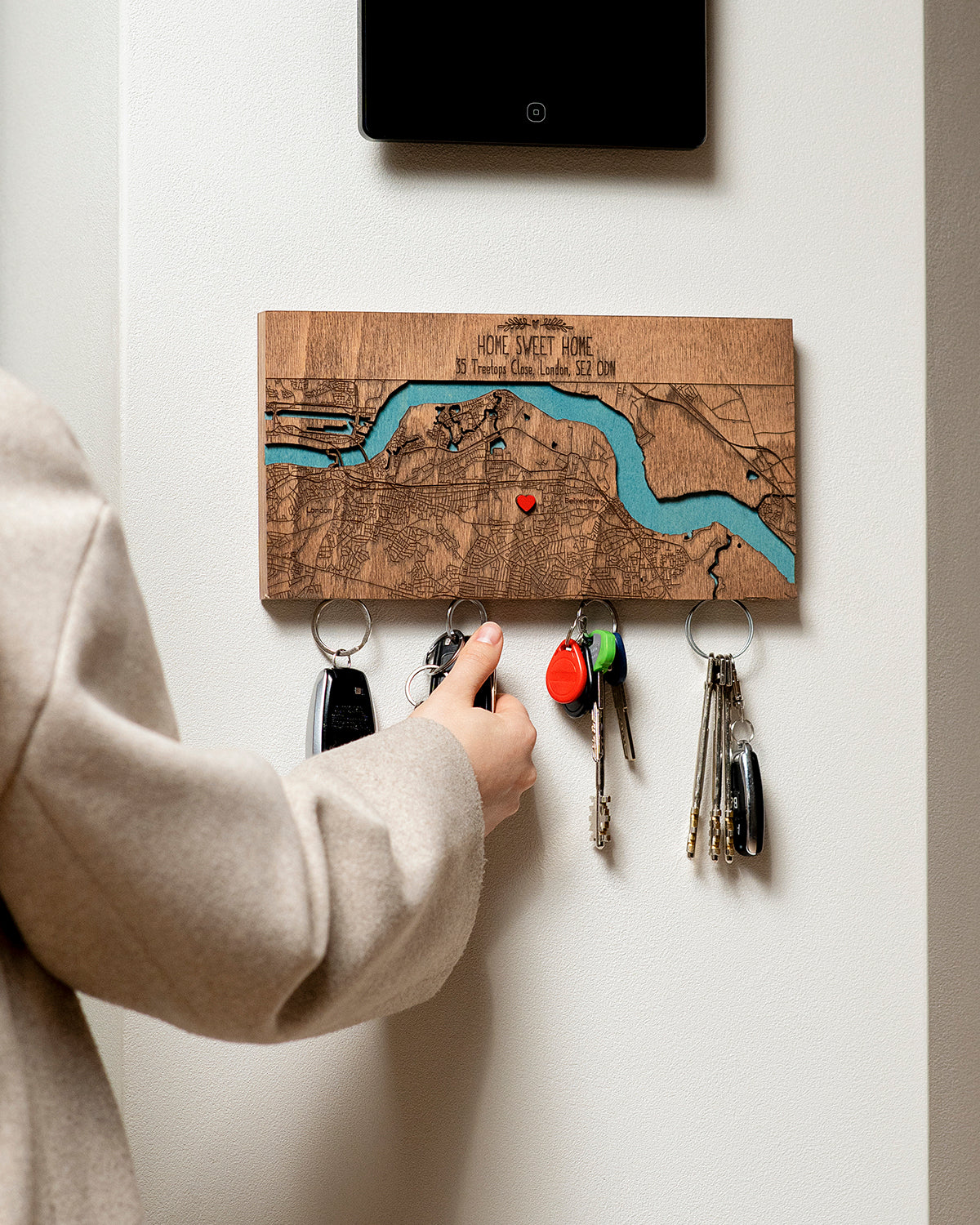 Person using a key holder with a map design on a white wall.