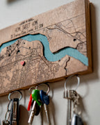 Wooden key holder with map design and keys attached, featuring a heart symbol on a wooden surface.