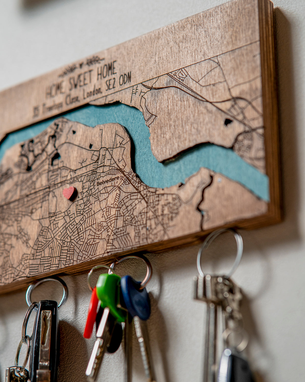 Wooden key holder with map design and keys attached, featuring a heart symbol on a wooden surface.