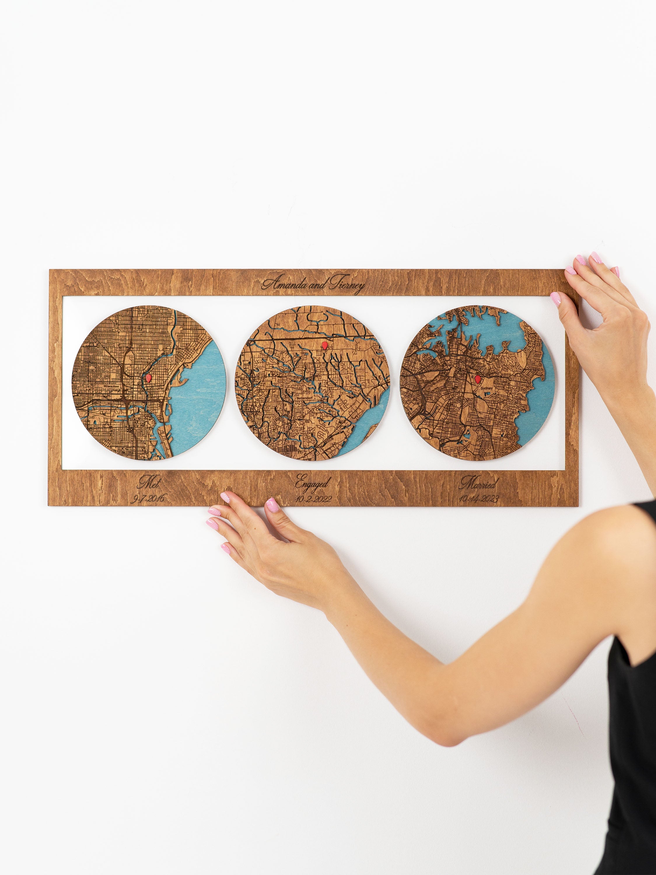 Custom wooden map wall art three circular sections showing different geographic locations marked with red pins. Each section is labeled with significant relationship milestones: "Met",Engaged", and "Married", along with specific dates under each label. On the frame has a personalized text.