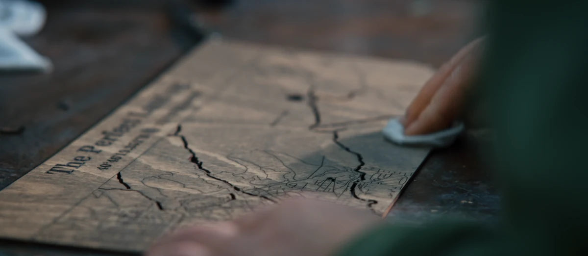 Hand finishing an engraved wooden map at the MurWoodHome workbench