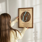 Woman hanging Our First Home Map custom address wall art in solid oak frame with personalized names and first home date