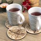 Personalized first home wooden coasters with engraved map design used under mugs on a table