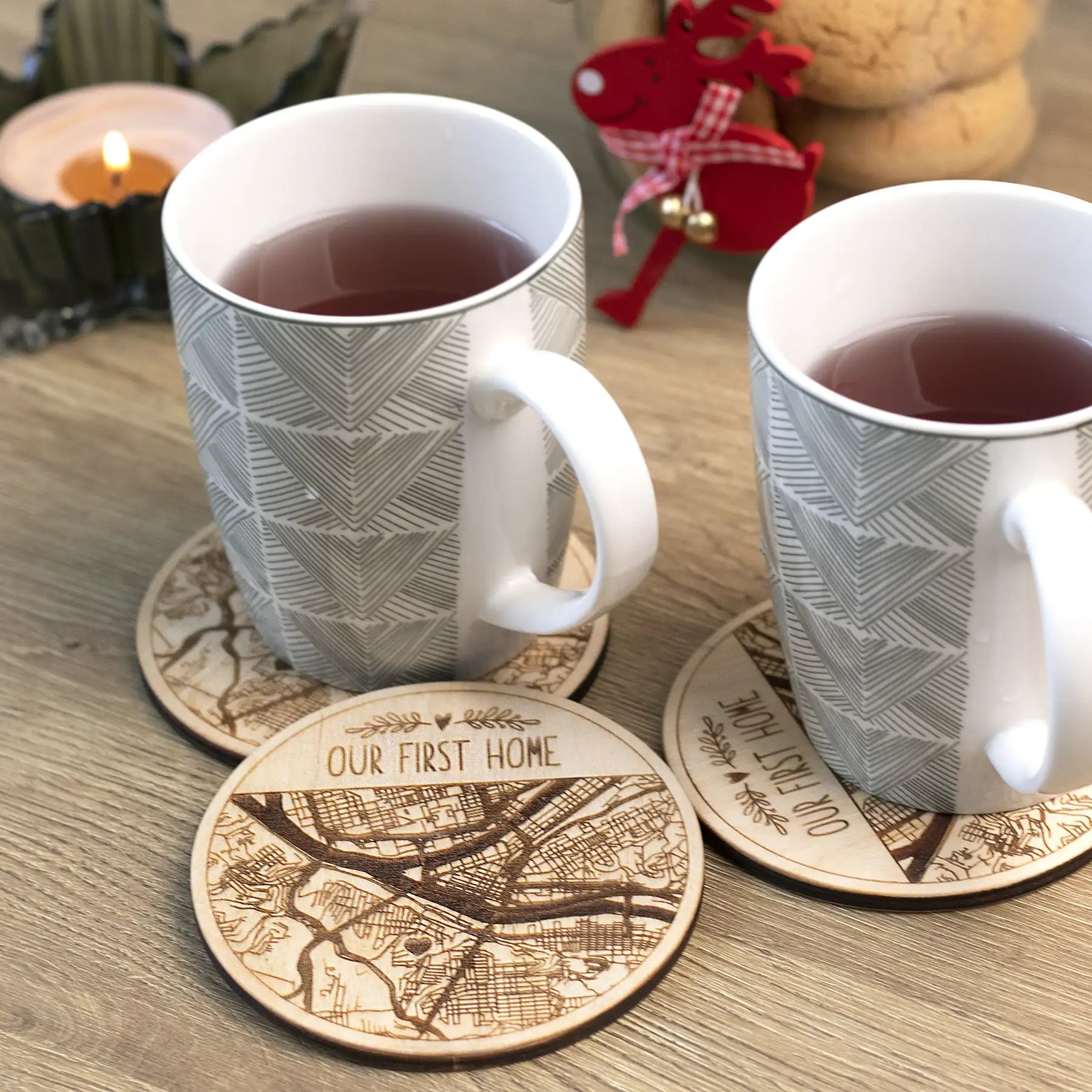 Personalized first home wooden coasters with engraved map design used under mugs on a table