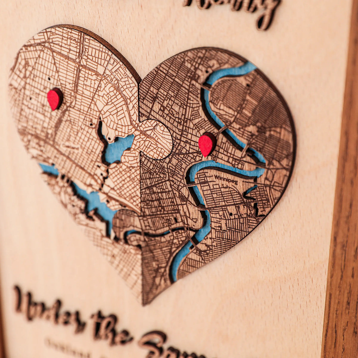 Detailed view of personalized heart location map with layered wood streets, blue rivers, red pins, and custom places.
