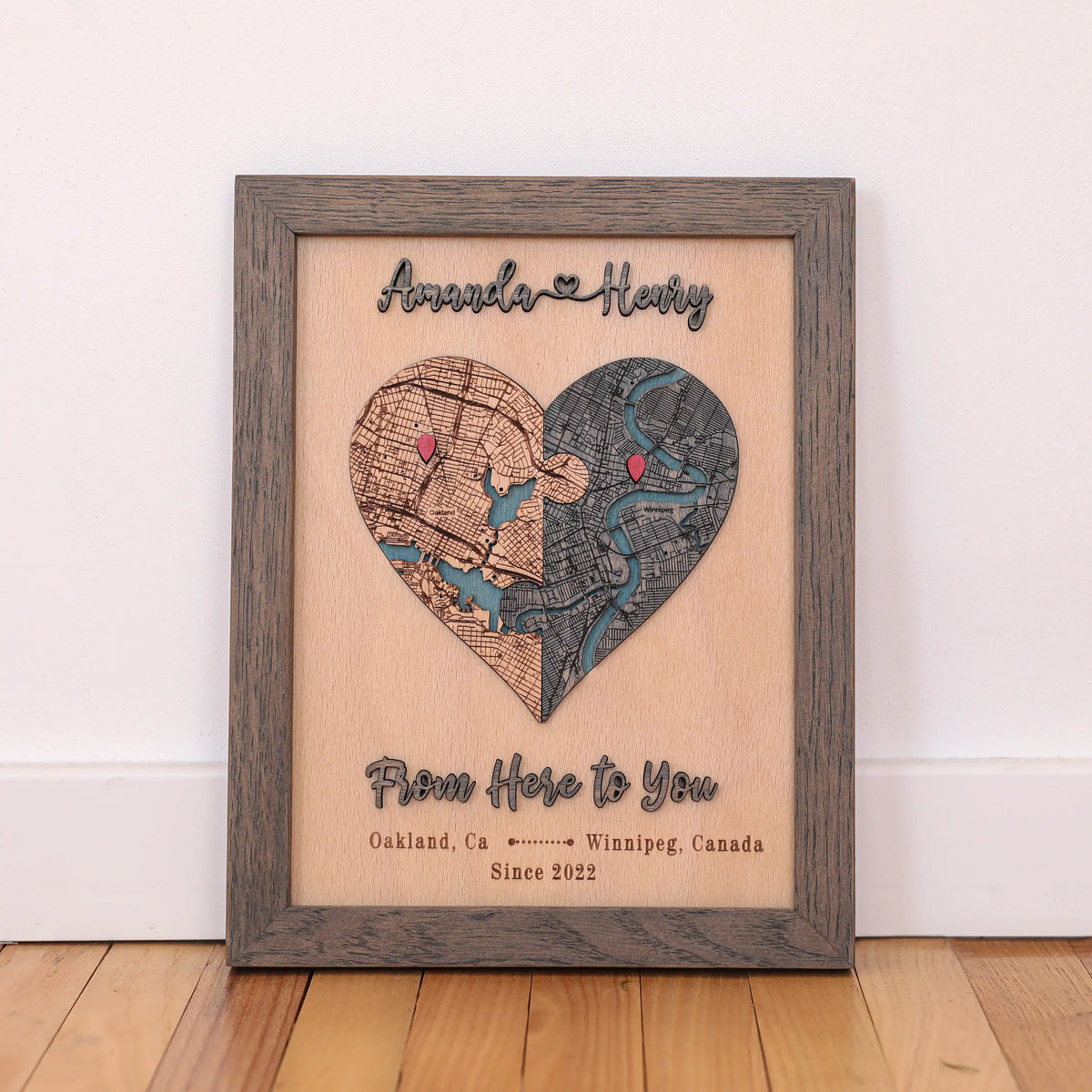 Personalized heart map for couples with two custom locations, red pins, raised lettering, and grey oak frame.