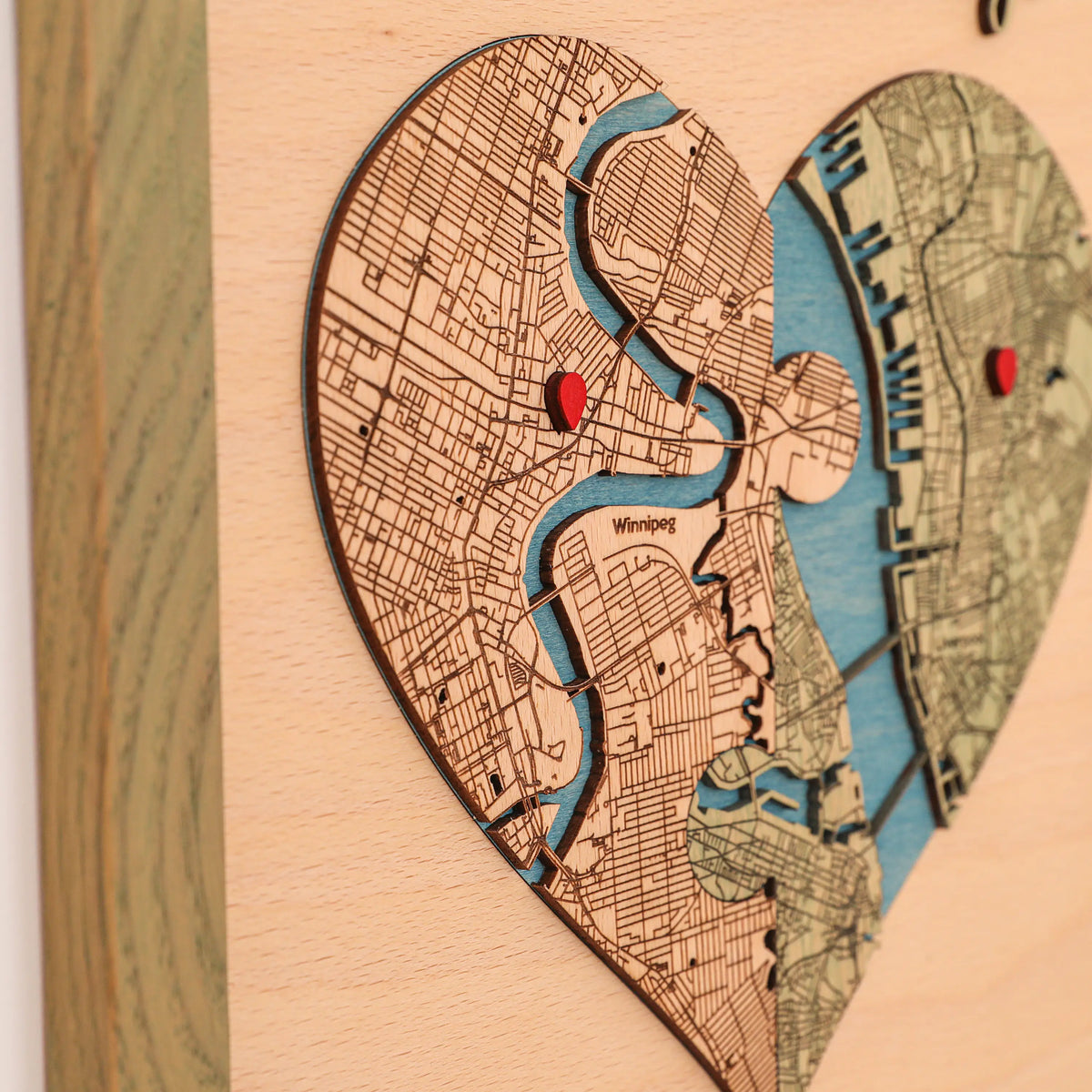Detailed view of personalized puzzle heart map with two custom locations, red pins, blue water, and sage frame.