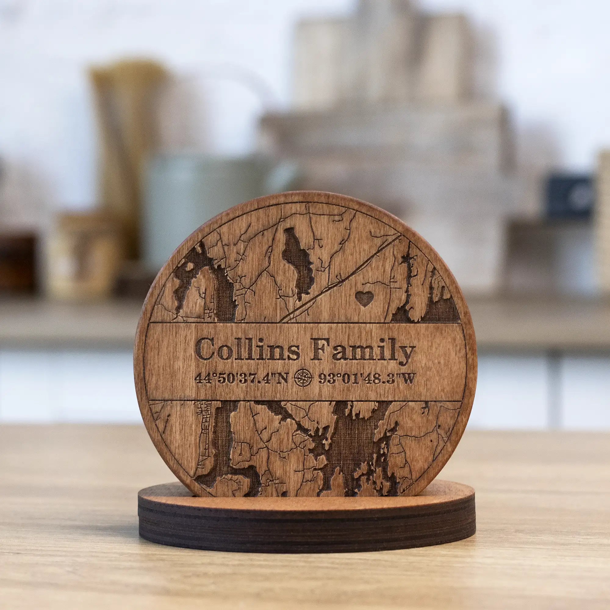 Personalized wooden coasters for housewarming with engraved family map design and matching holder on table