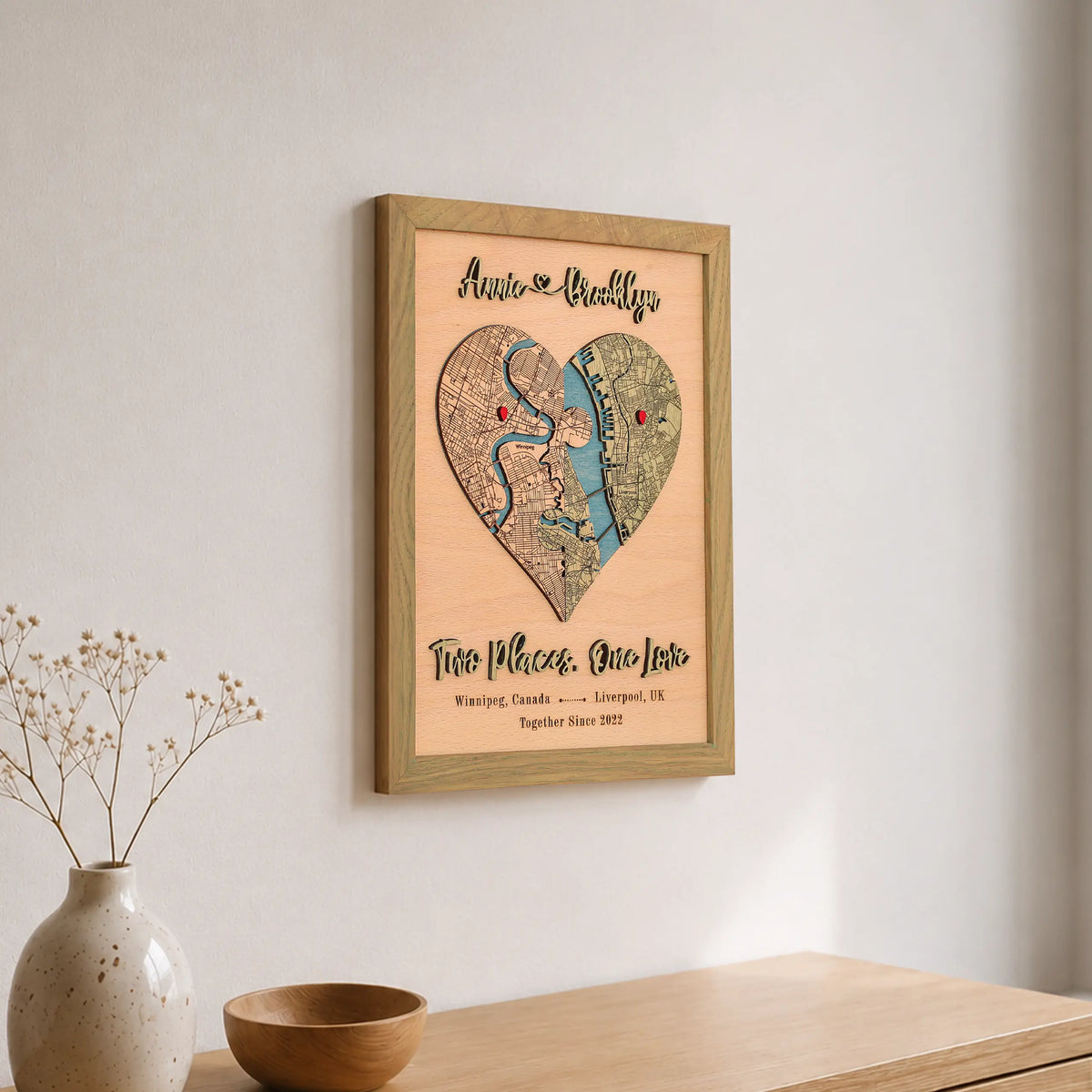 Personalized wooden heart map in sage frame displayed on a wall with custom locations and romantic wording.