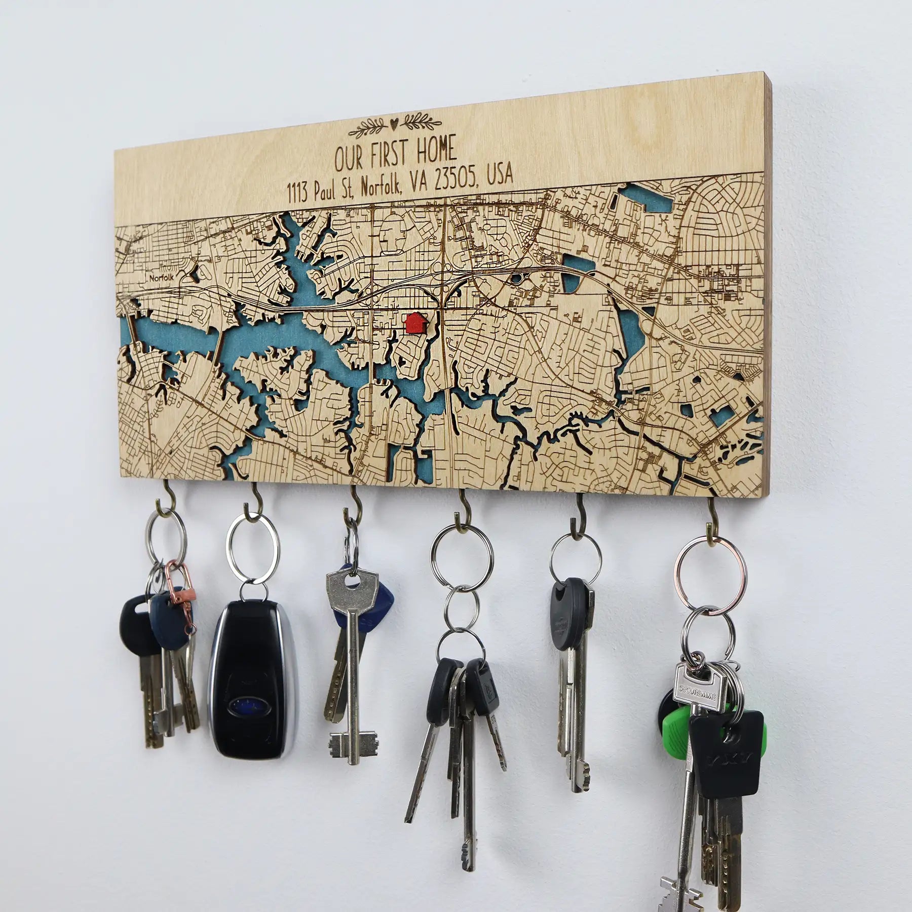 Angled view of a personalized wooden wall key holder with hooks showing custom map detail and multiple key sets