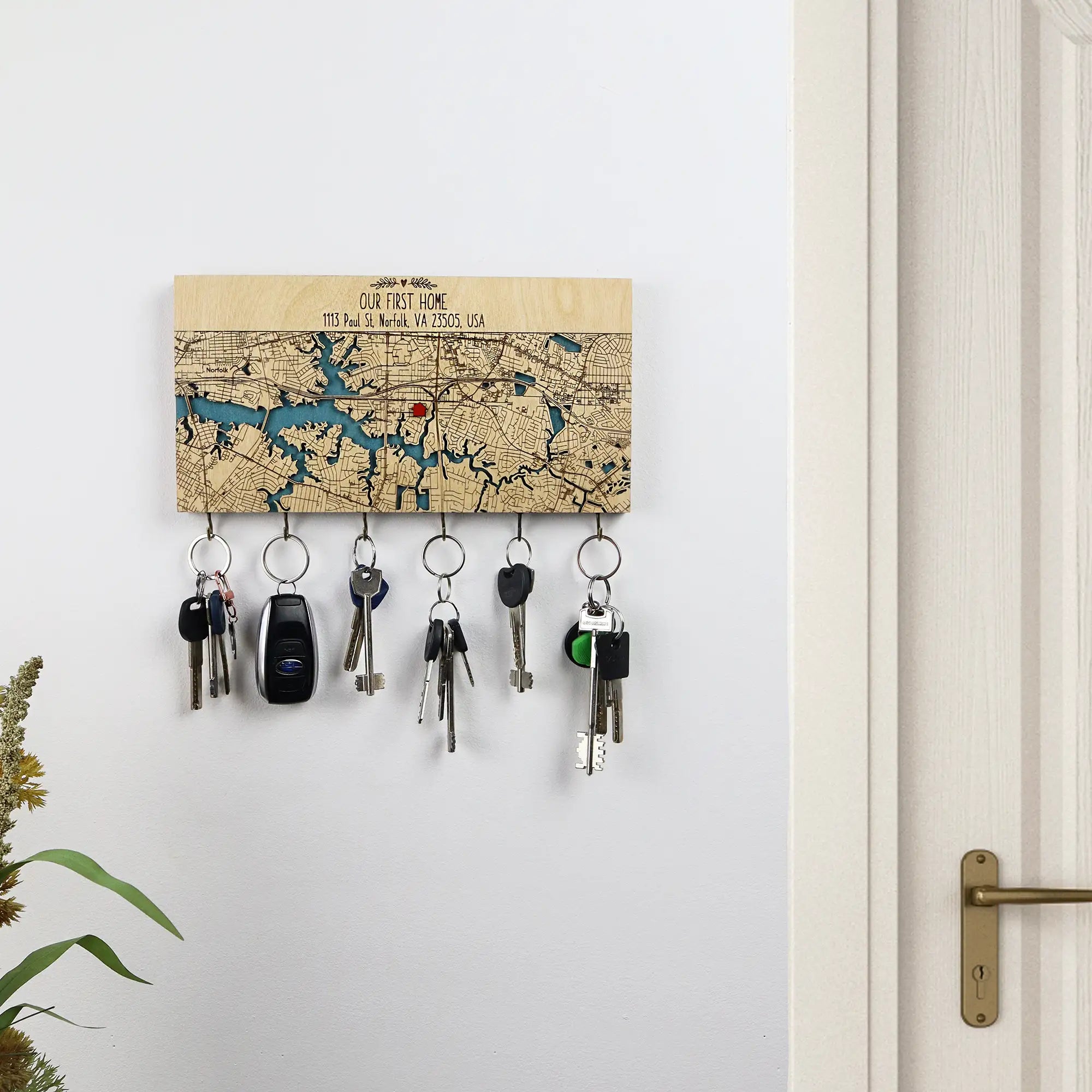 Wall mounted wooden key holder with hooks personalized with home map displayed near doorway
