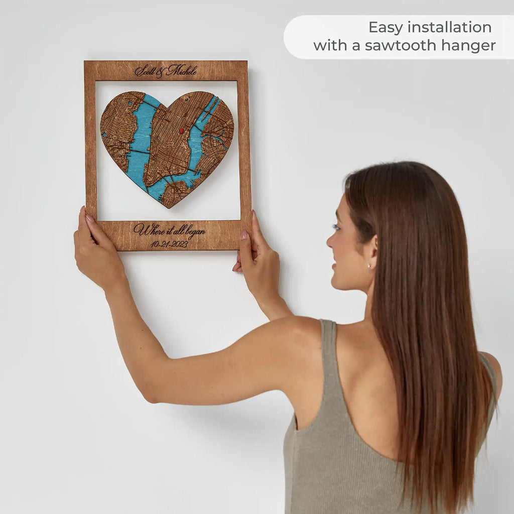 Woman hanging personalized Where It All Began wooden map on wall with easy sawtooth hanger installation