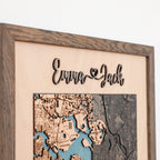 Close-up of wooden anniversary gift for him with raised 3D couple names, custom map detail, and oak frame.