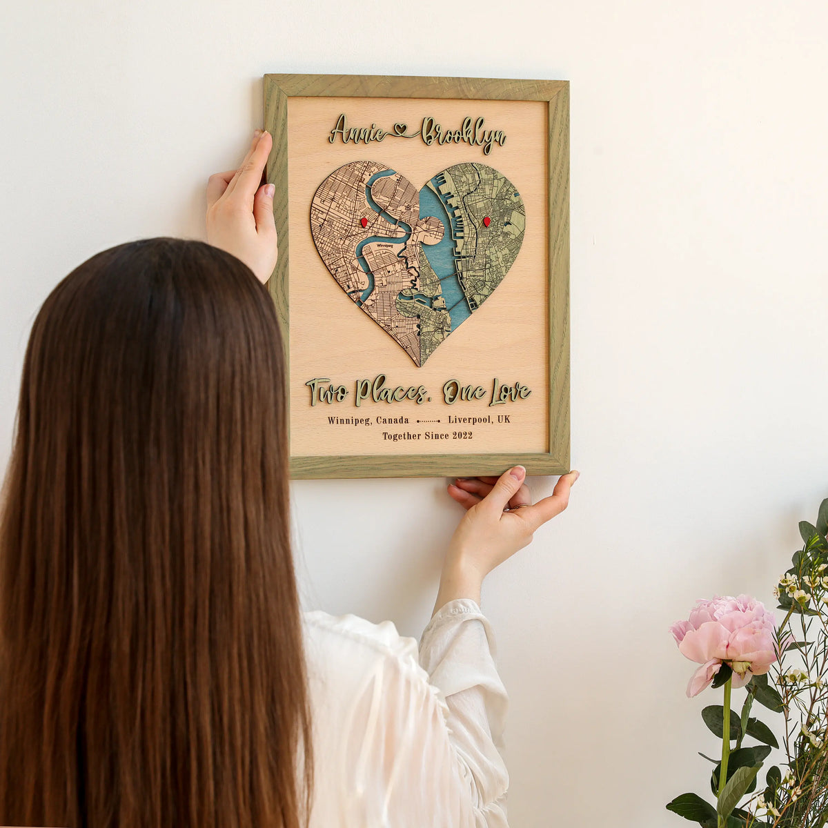 Close-up of wooden couple map with raised 3D names, puzzle heart design, and personalized two-location map.