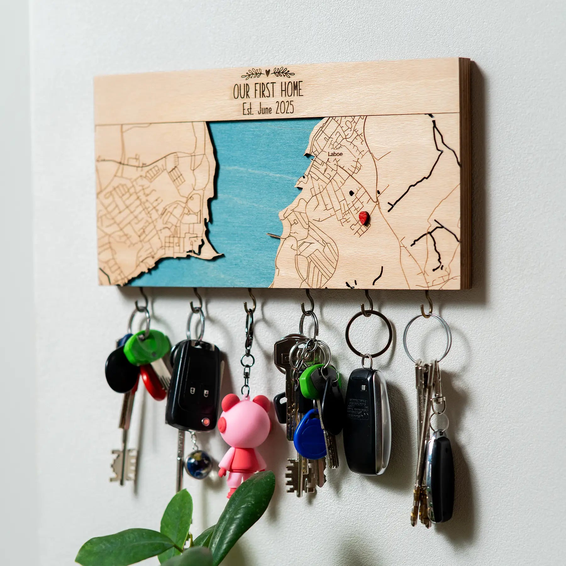Angled view of wall mounted wooden key holder with hooks personalized with first home map design
