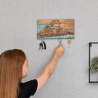 Child hanging keys on wooden key rack for wall with personalized first home map design