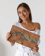 Woman holding a wooden map keychain with keys attached on a plain background