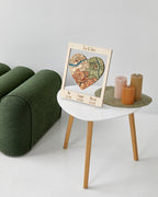 Decorative heart-shaped map on a stand with candles on a small table in a room.